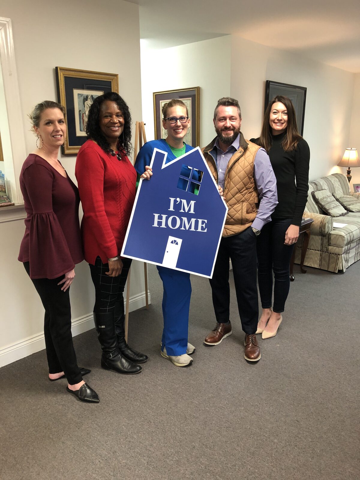 Staff and a new homeowner holding an “I'm Home” sign